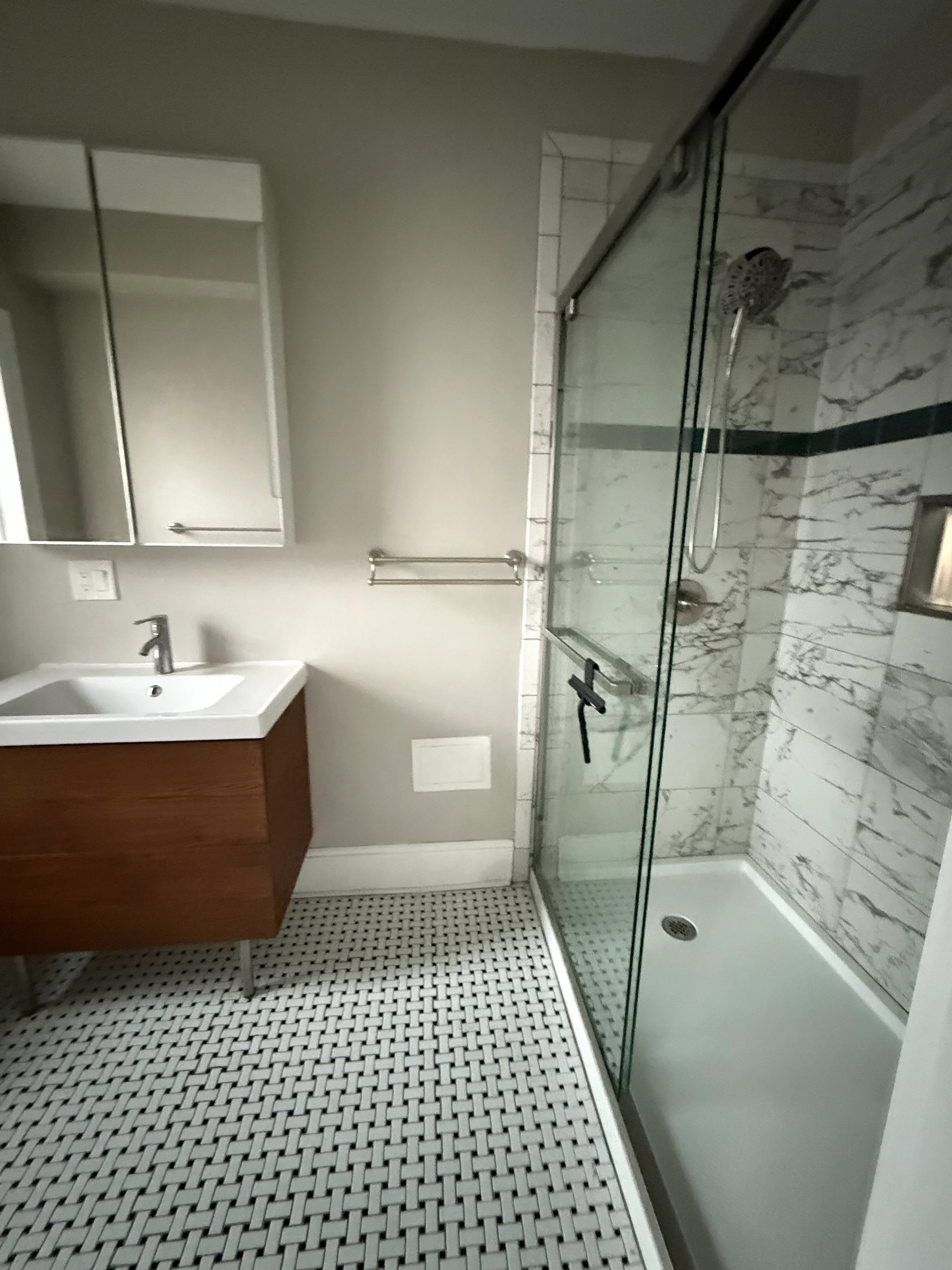 Bathroom with marble-effect tile, a patterned mosaic feature wall and a glass shelf