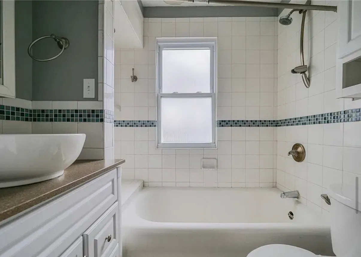 Bathroom with white tile, a glass mosaic border and a vessel sink