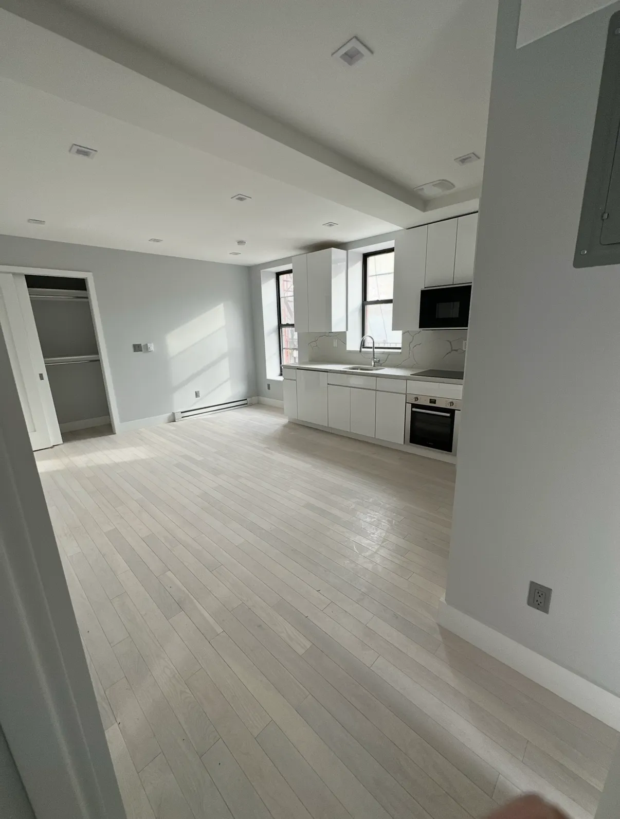 Open-plan living room and kitchen with pale wood floors and recessed lighting